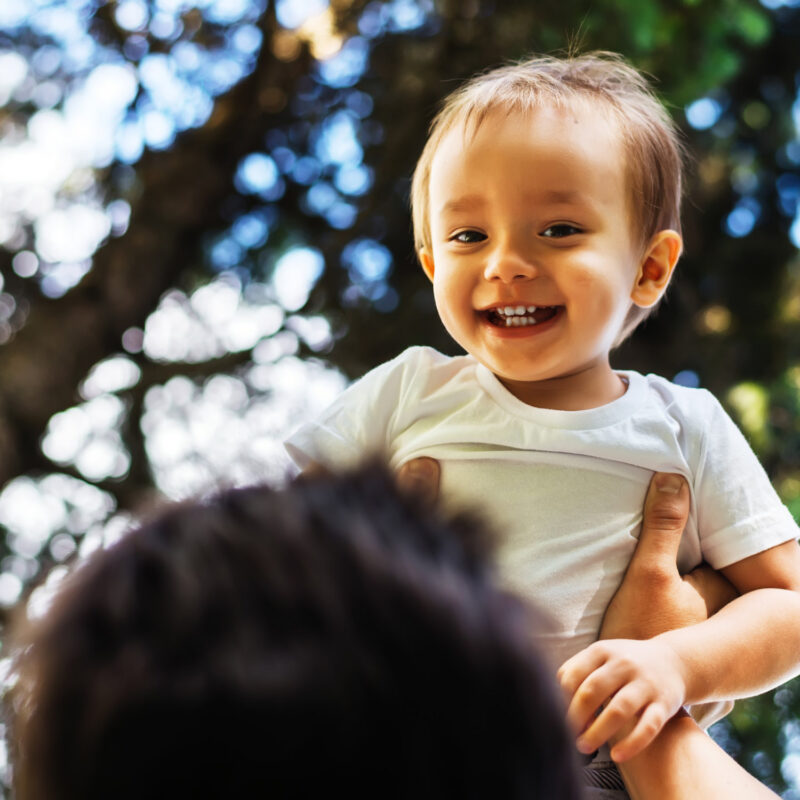 A young child being picked up by dad while smiling